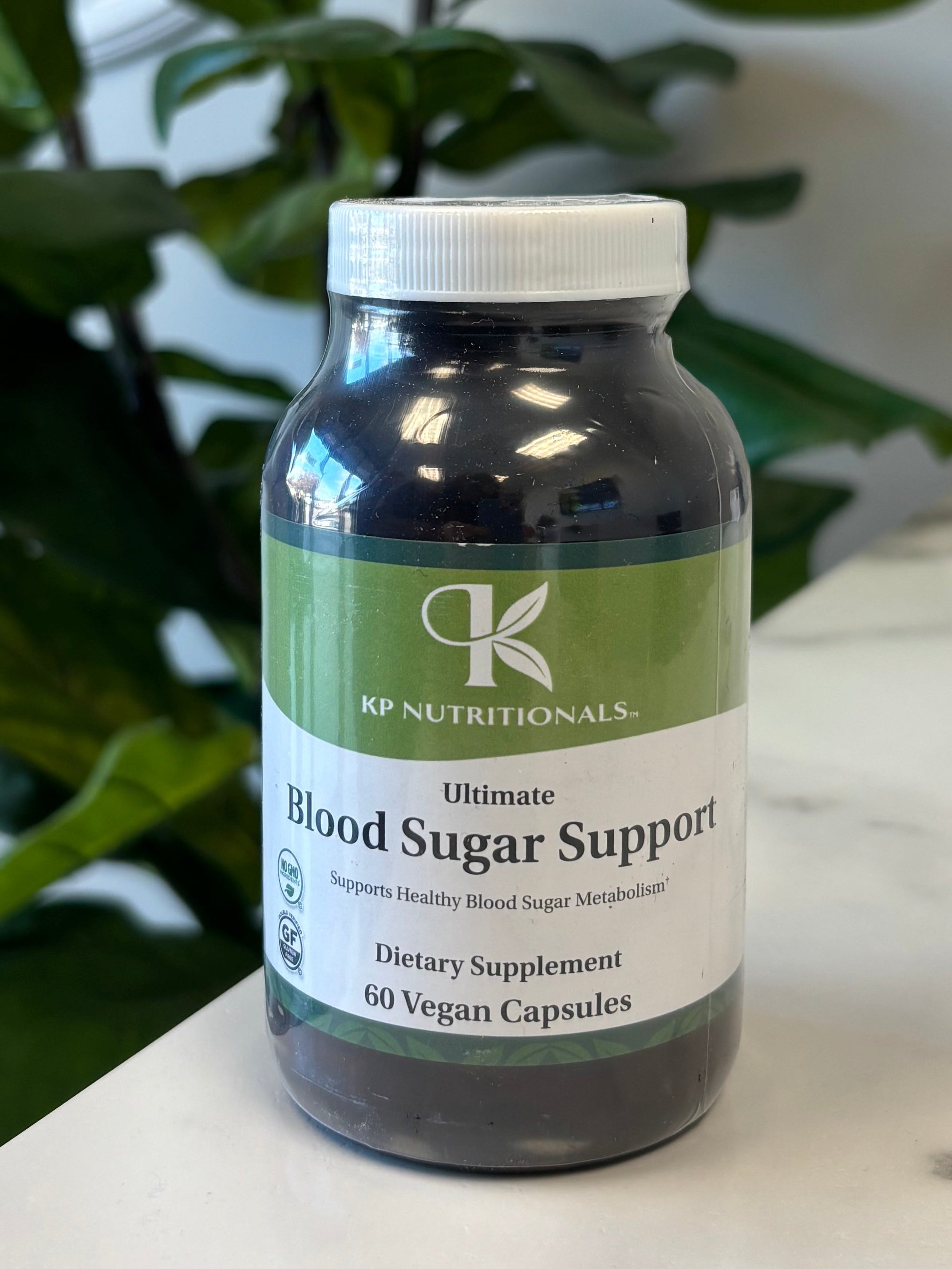 Bottle of Blood Sugar Support supplement with a plant in the foreground on a marble counter